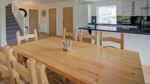Una cocina amplia con mesa y sillas de madera, una isla integrada y una escalera que sube a otro nivel.