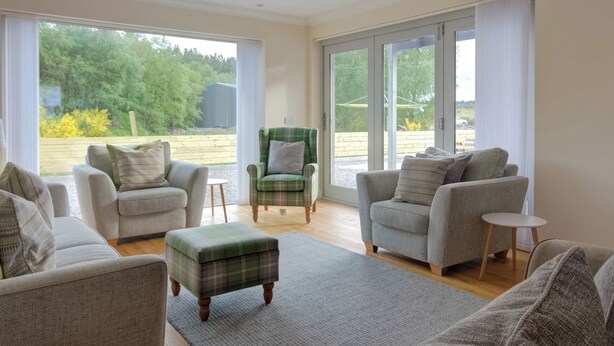 Un salón amplio con un gran ventanal, un sillón verde y dos sofás.