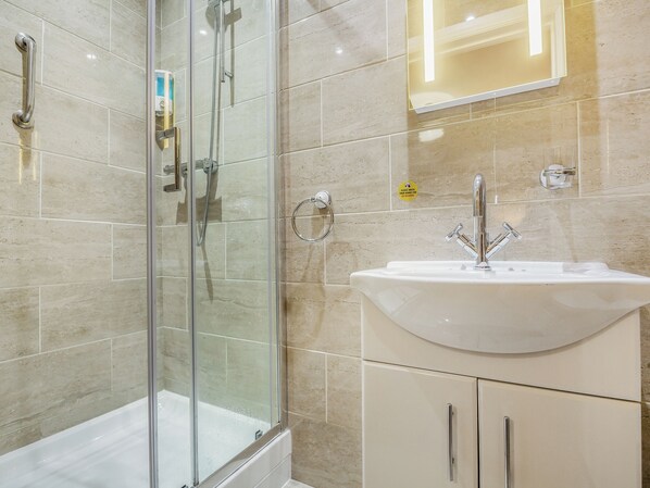 A modern bathroom with a glass-enclosed shower, a white sink, and a mirror above it. - Bryn Awelon - UK44122 (Moelfre, near Benllech)