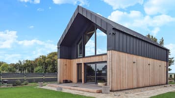 A modern house with a sloped roof, large windows, and a wooden exterior.