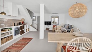 Eine moderne Küche mit weißen Schränken, einem Holztisch und einer gewobenen Pendelleuchte.