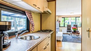 Cocina compacta con lavamanos, estufa y ventana con vista a un patio trasero.