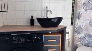 A compact kitchen with a black washing machine, a sink with a black basin, and a toilet. - Lovely studio in the artists' quarter (Sète)
