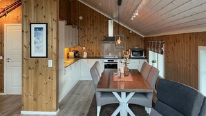A compact kitchen with wooden walls, a dining table with four chairs, and a small TV. - Amazing home in Oppdal (Oppdal)