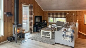 A cozy living room with a wood-burning stove, a sofa, a TV, and a fireplace. - Amazing home in Oppdal (Oppdal)