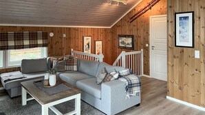 A cozy room with a grey sofa, a wooden coffee table, and a white railing. - Amazing home in Oppdal (Oppdal)