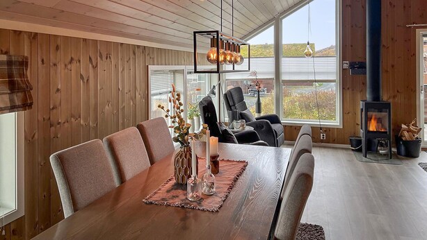 A modern dining area with a wooden table, chairs, and a central light fixture. - Amazing home in Oppdal (Oppdal)