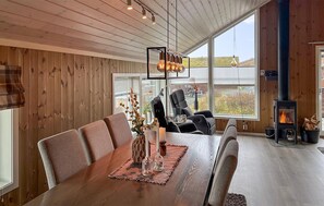Een moderne eetruimte met een houten tafel, stoelen en een centraal hanglamp.