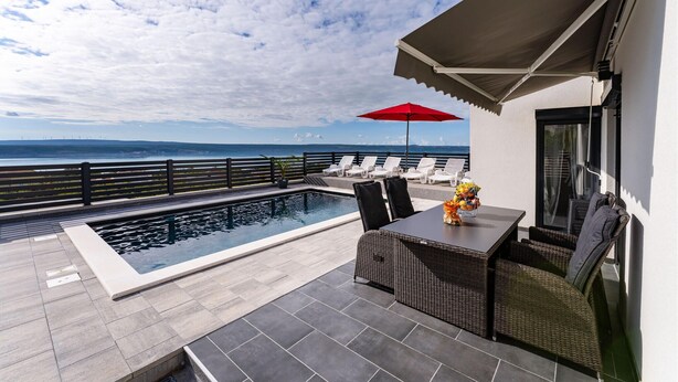 A rooftop pool area with a view of the ocean, a covered seating area, and a table with a fruit basket. - Cozy home in Maslenica (Maslenica)
