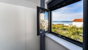 A room with a large window offering a view of a coastal landscape, including a body of water and distant hills. - Cozy home in Maslenica (Maslenica)
