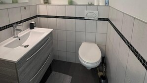 A compact bathroom with a white sink, vanity, and toilet.