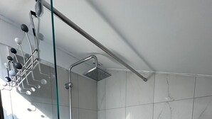 A shower with a glass door, a handheld showerhead, and a wall-mounted faucet.