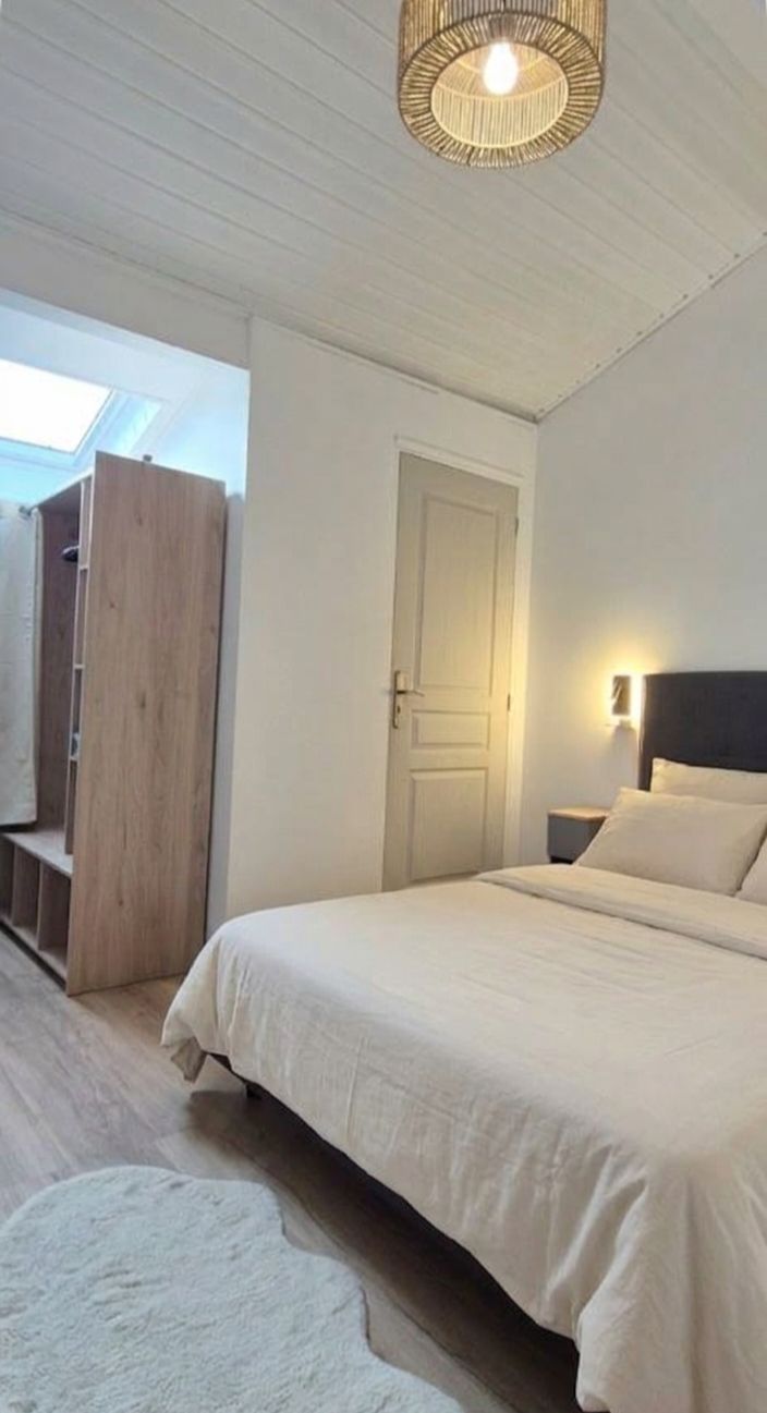 Een slaapkamer met een bed, een deur, een nachtkastje, een wandlamp en een plafondventilator.