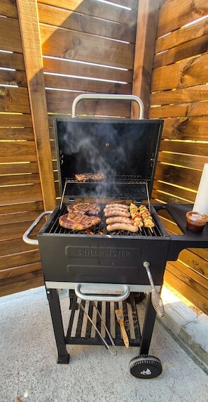A GRILLMEISTER barbecue grill with multiple cooking grates and a chimney, set against a wooden backdrop. - Cozy 2-room apartment in a quiet neighborhood near Lake Geneva, with parking and a terrace (Allinges)