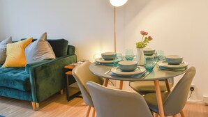 A dining area with a round table, chairs, and a vase with flowers.