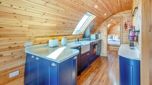 A modern kitchen with wooden walls, a skylight, and a built-in sink. - This luxury lodge with a private hot tub is perfect for exploring Mid Wales. (St Harmon, near Rhayader)