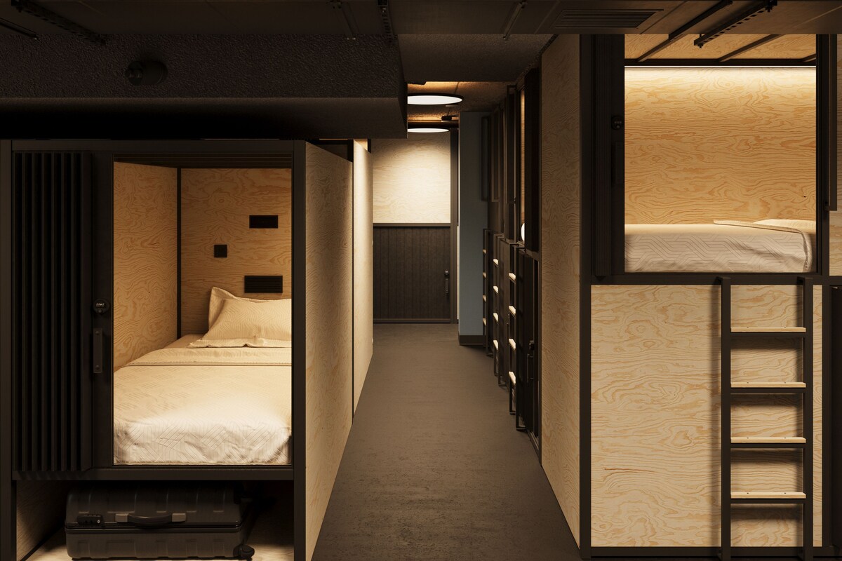 A compact hotel room with bunk beds, a small desk, and a wardrobe.