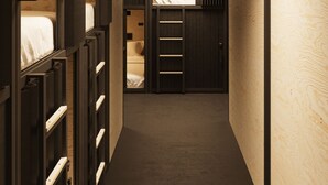 A narrow hallway with bunk beds on one side and a small room with a bed on the other. - Podtel (Honolulu)