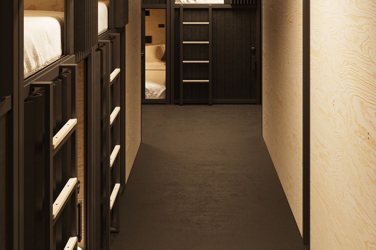 A narrow hallway with bunk beds on one side and a small room with a bed on the other.