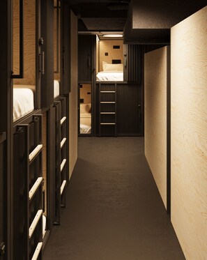 A narrow hallway with bunk beds on one side and a small room with a bed on the other. - Podtel (Honolulu)