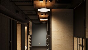 A narrow hallway with bunk beds on both sides, wooden walls, and a ceiling with exposed pipes and lighting fixtures.
