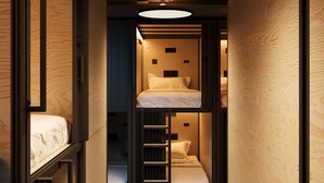A narrow hallway with a bunk bed and a ladder leading to a lower bunk. - Podtel (Honolulu)