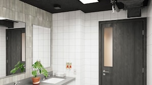 A modern bathroom with two sinks, a large mirror, and a potted plant.