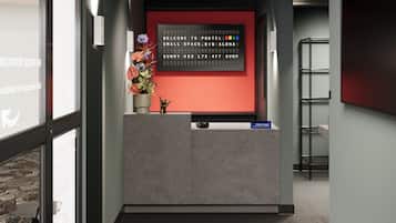 A reception area with a modern design, featuring a reception desk, a welcome sign, and a potted plant.