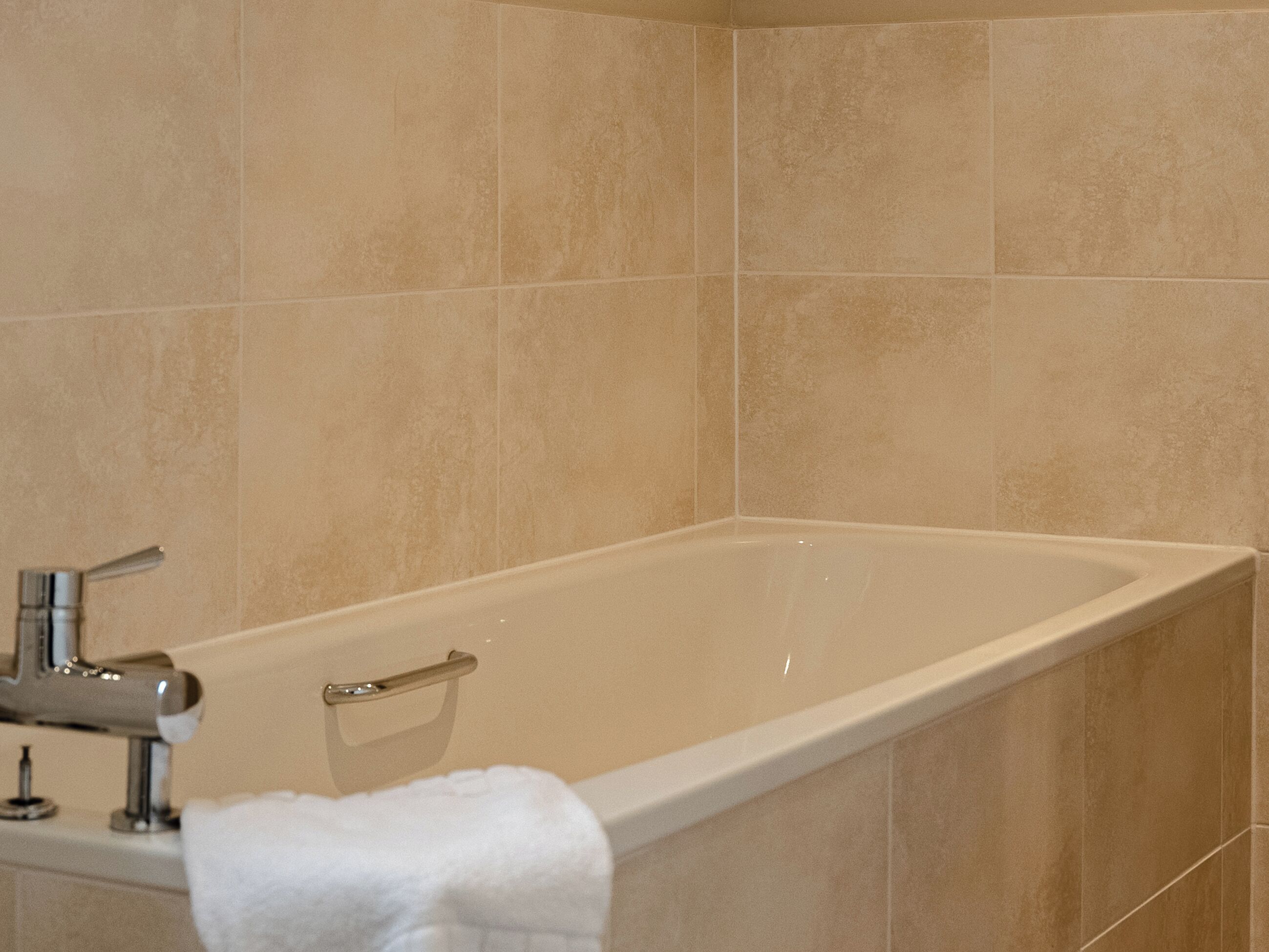 A bathroom with a bathtub, a faucet, and a towel rack.