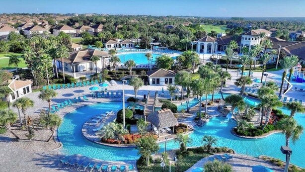 A resort with multiple swimming pools, palm trees, and a golf course in the background. - Spacious 5Bdr 5Bth ChampionsGate Villa Near Disney, Private Pool & Resort Access (Davenport)