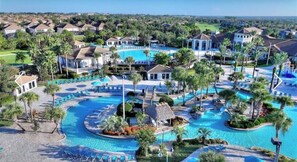 Un resort con varias piscinas, palmeras y un campo de golf al fondo.