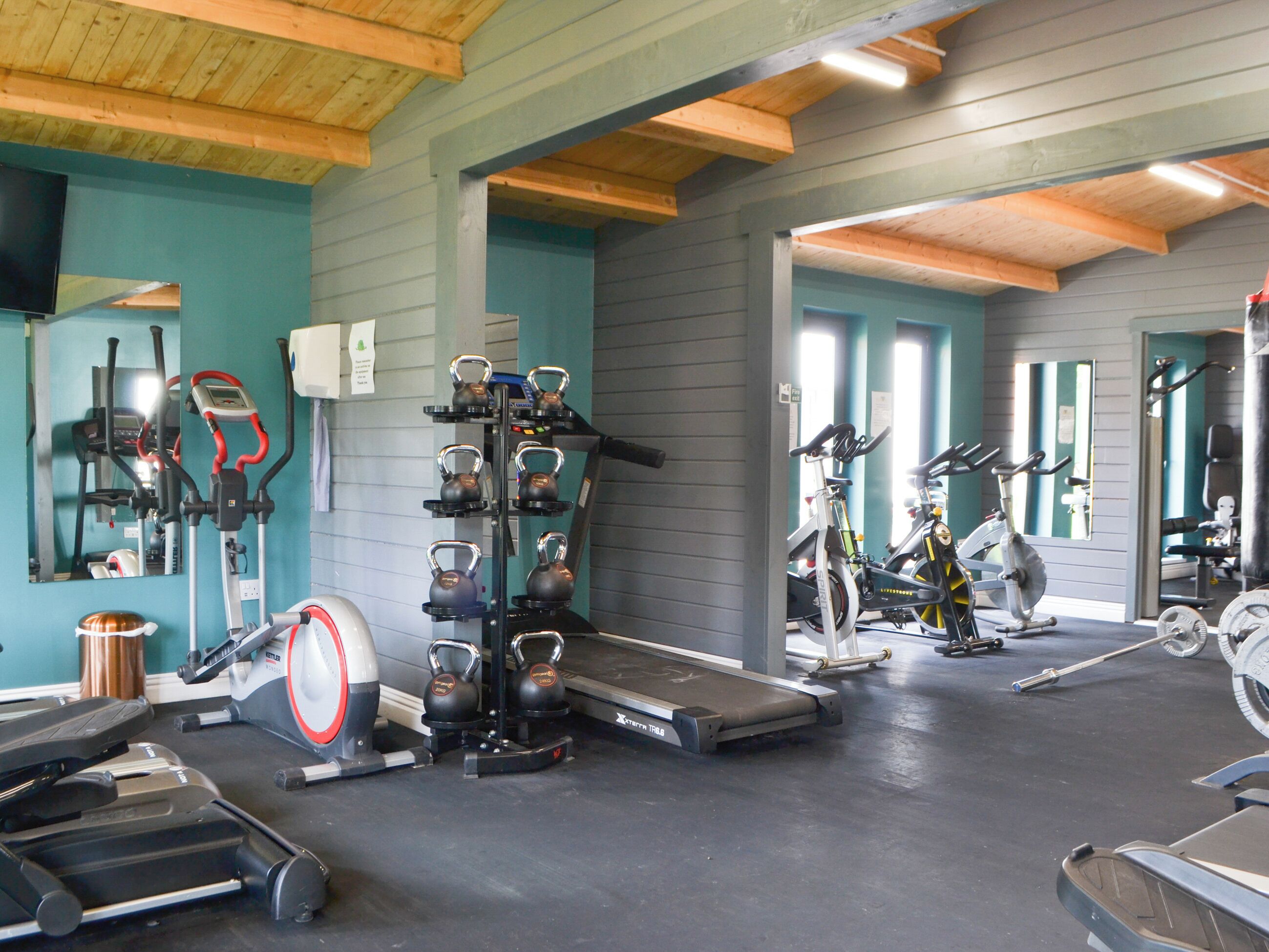 A gym with various exercise equipment, including treadmills, stationary bikes, and kettlebells.