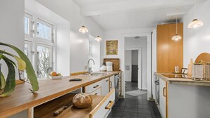 A modern kitchen with a wooden countertop, a bread loaf, and a knife. There is a window with a view of trees outside.