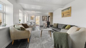 A spacious living room with a fireplace, a dining area, and a kitchen in the background.