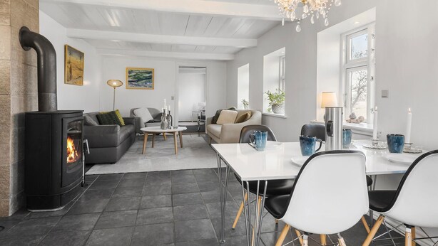 A modern living room with a fireplace, a dining area, and a chandelier.