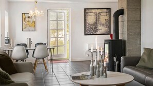 A modern living room with a fireplace, a dining area, and a large window.