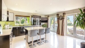 Una cucina moderna con isola centrale, sgabelli da bar e tavolo da pranzo.