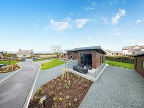 Un bâtiment moderne avec une allée pavée, un jardin aménagé et un ciel dégagé.