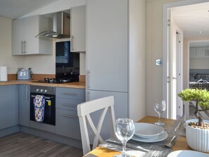 A modern kitchen with grey cabinets, a stove, and a dining area with a table set for two.