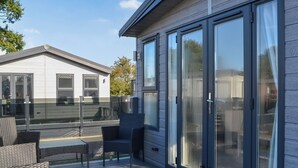 Una casa moderna con terraza, mobiliario exterior y amplios ventanales correderas.