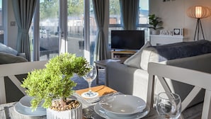 Una sala de estar moderna con sofá, televisor y comedor con una mesa para dos.