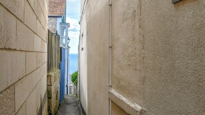 Un callejón estrecho con un cartel de número de casa en la pared derecha.