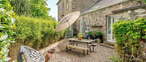 A stone building with a patio area, outdoor seating, and potted plants.