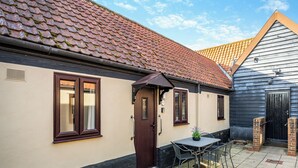 Une maison avec un toit en tuiles, une porte et un petit patio avec une table et des chaises.
