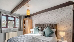 Une chambre avec un grand lit, une armoire en bois, un radiateur et une fenêtre avec des rideaux.