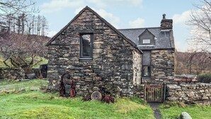 Ein Haus aus Stein mit einem Satteldach, einem kleinen Fenster und einem Schornstein.