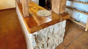 Une cuisine rustique avec des poutres apparentes, un plan de travail en pierre et un sol carrelé.