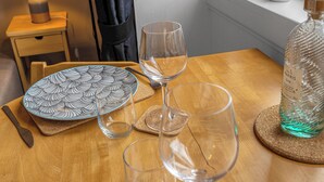 A wooden table with a plate, two wine glasses, a bottle of gin, and a lamp. - Top Floor Spacious King Size Apartment | City Views | Excellent Transport Links (Edinburgh)