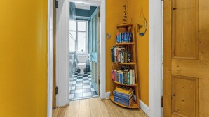 A hallway with a wooden bookshelf, a wooden door, and a checkered floor. - Top Floor Spacious King Size Apartment | City Views | Excellent Transport Links (Edinburgh)