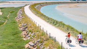 A paved path alongside a body of water, bordered by a stone wall and vegetation. - Amazing home in Gueschart with house sea view (Gueschart)
